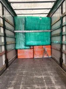 Streç ve koruma ile paketlenmiş ev eşyasının tenteli dorse içinde istiflenmiş hâli