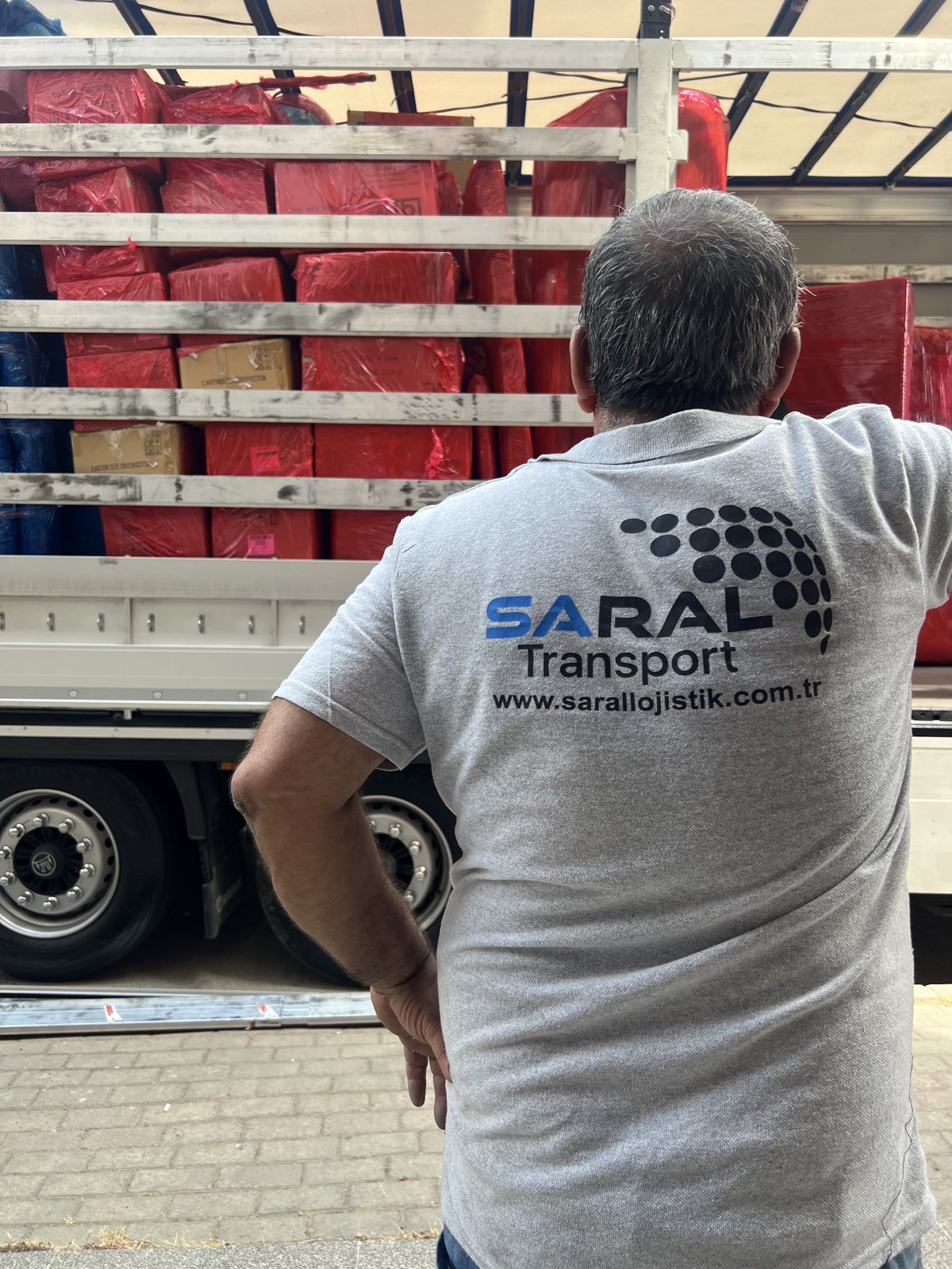 Saral Transport tişörtlü ekip üyesi yüklenmiş dorsenin son kontrolünü yaparken